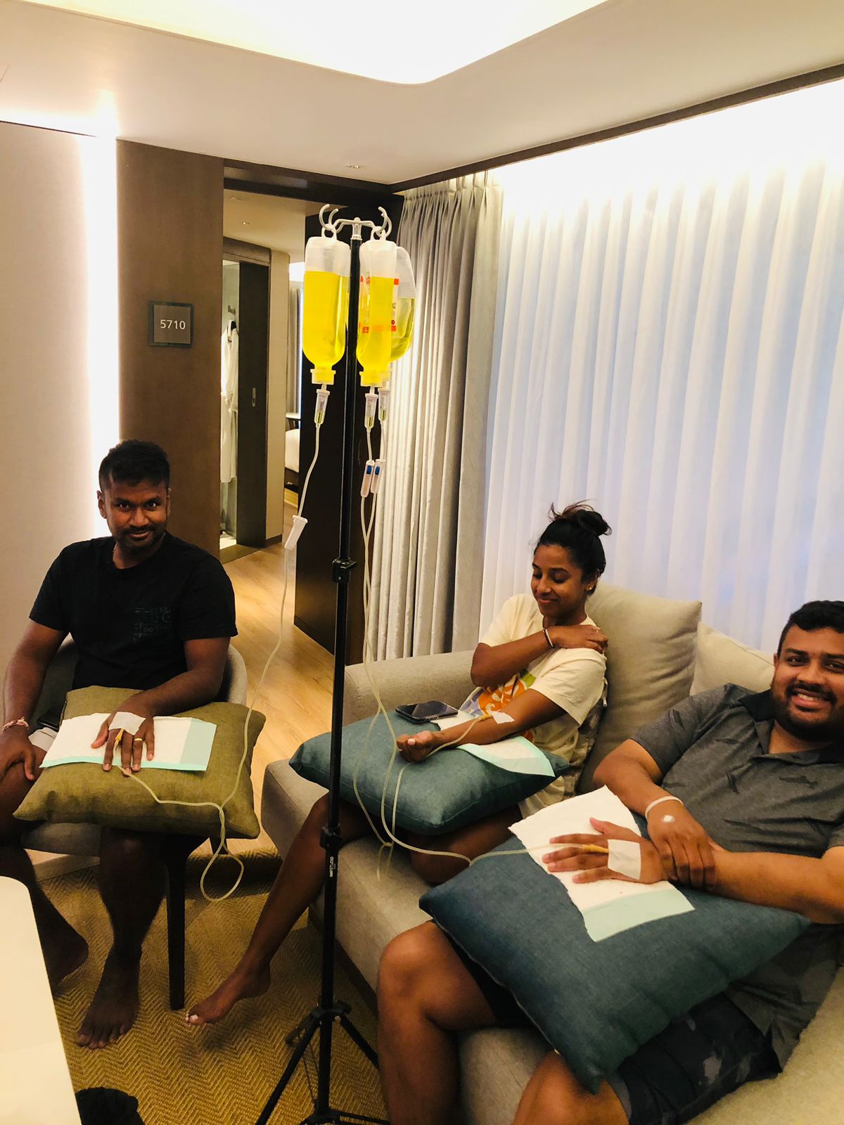 Three people receiving mobile IV drip therapy while relaxing in a villa lounge.