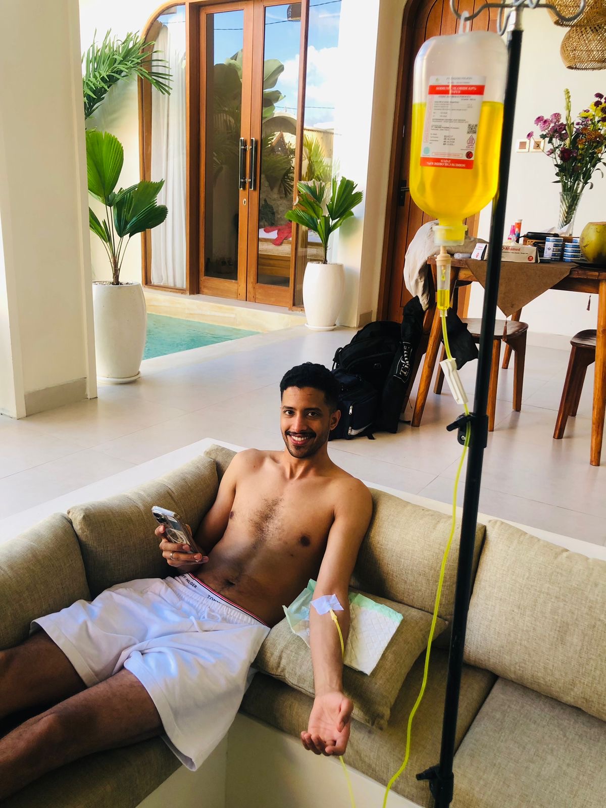 Man relaxing on a sofa in a Bali villa while receiving a mobile IV drip therapy.